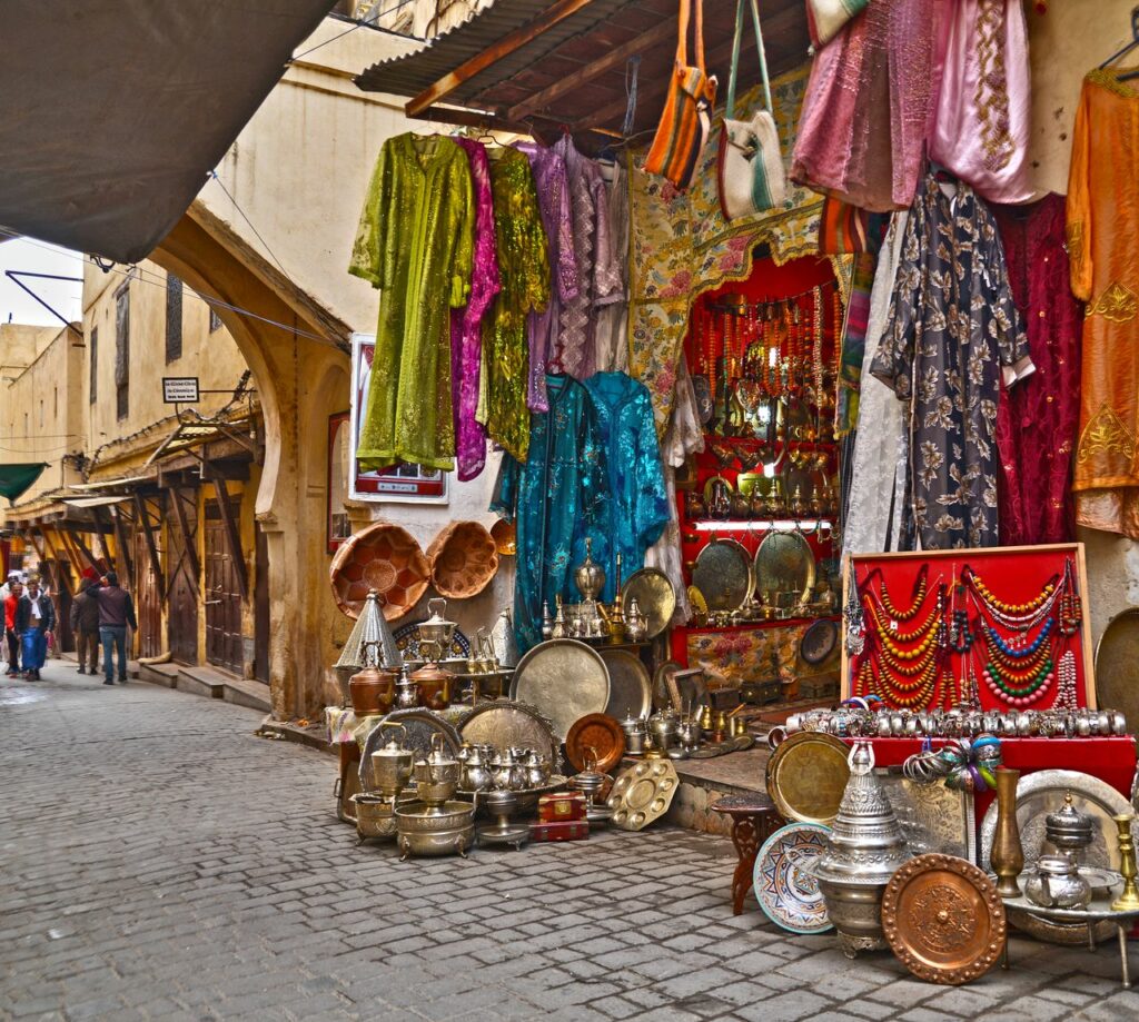 Vibrant market stall in Fès, showcasing colorful fabrics and metalware on display.
